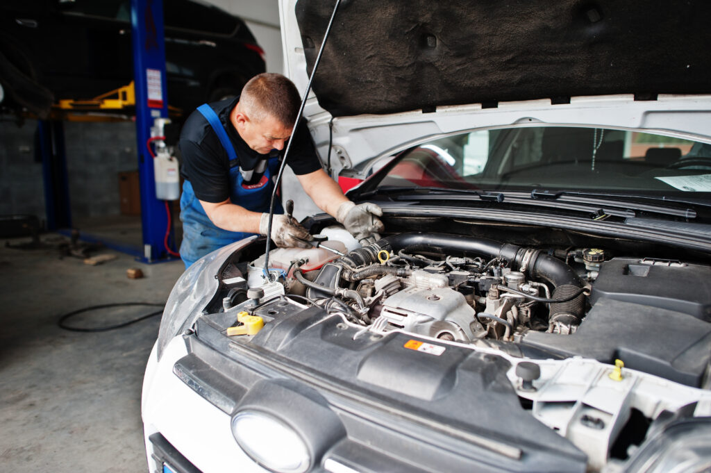 car-repair-and-maintenance-theme-mechanic-in-uniform-working-in-auto-service-checking-engine-1024x681